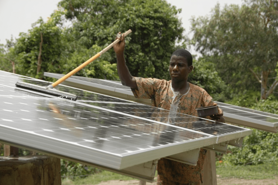 A solar technician from SELF’s local NGO partner washes panels in the village of Dunkassa in northern Benin. (Credit: Solar Electric Light Fund)